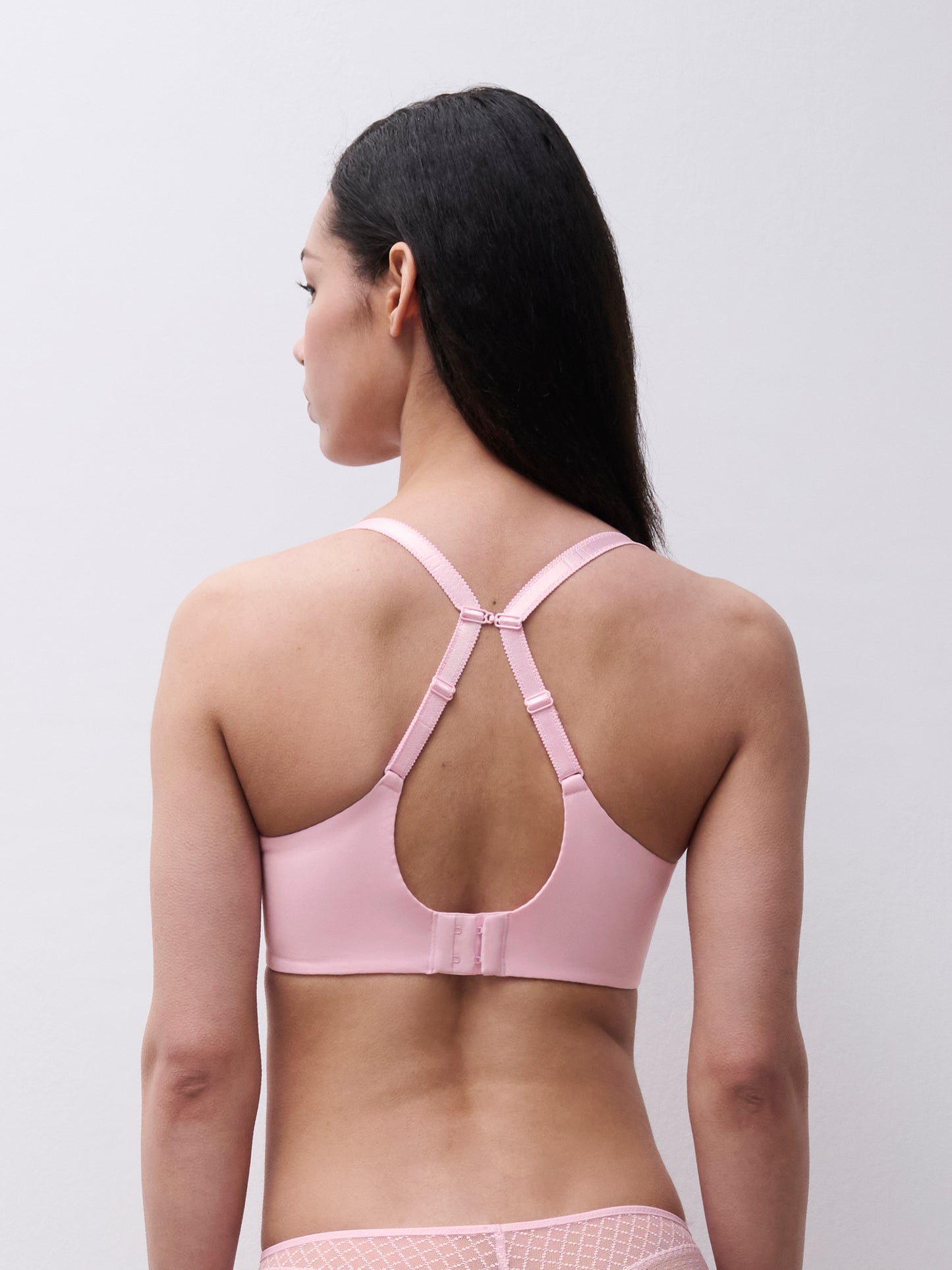 Woman wearing a pink bralette against a plain background