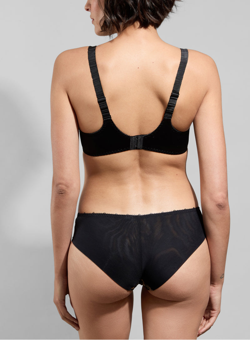 Person wearing a black bra and underwear set on a gray background