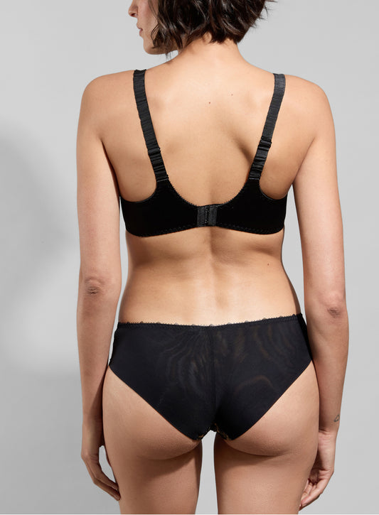 Person wearing a black bra and underwear set on a gray background