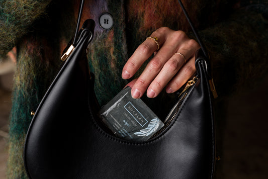 Hand holding a black leather handbag with a visible brand label.