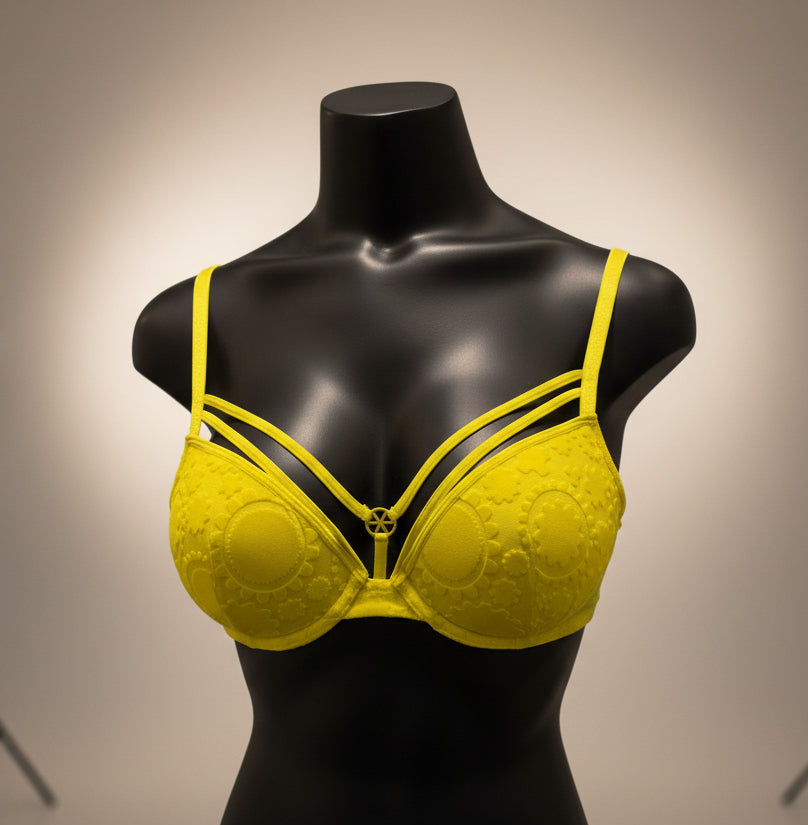 Yellow bikini top on a mannequin against a dark background