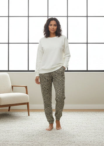 Mannequin wearing a white top and leopard print pants on a plain background
