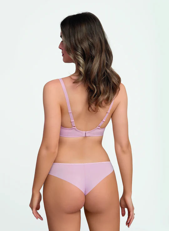 Woman wearing a light pink lingerie set on a plain background