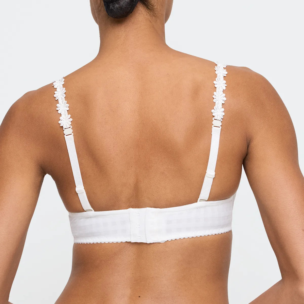 White bra worn by a person on a plain background
