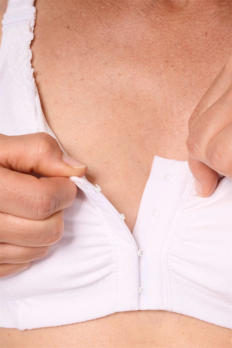 Close-up of a person wearing a white bra with a plain background