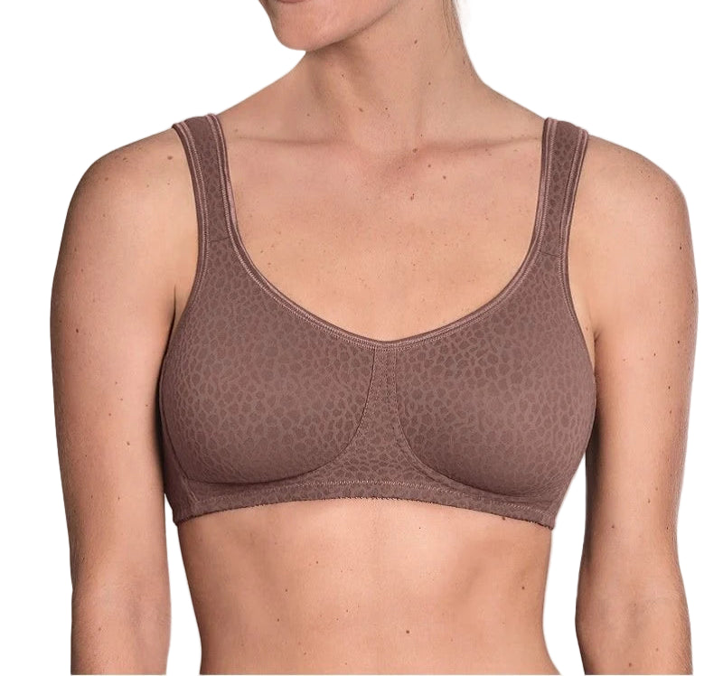 Woman wearing a brown bralette against a plain background