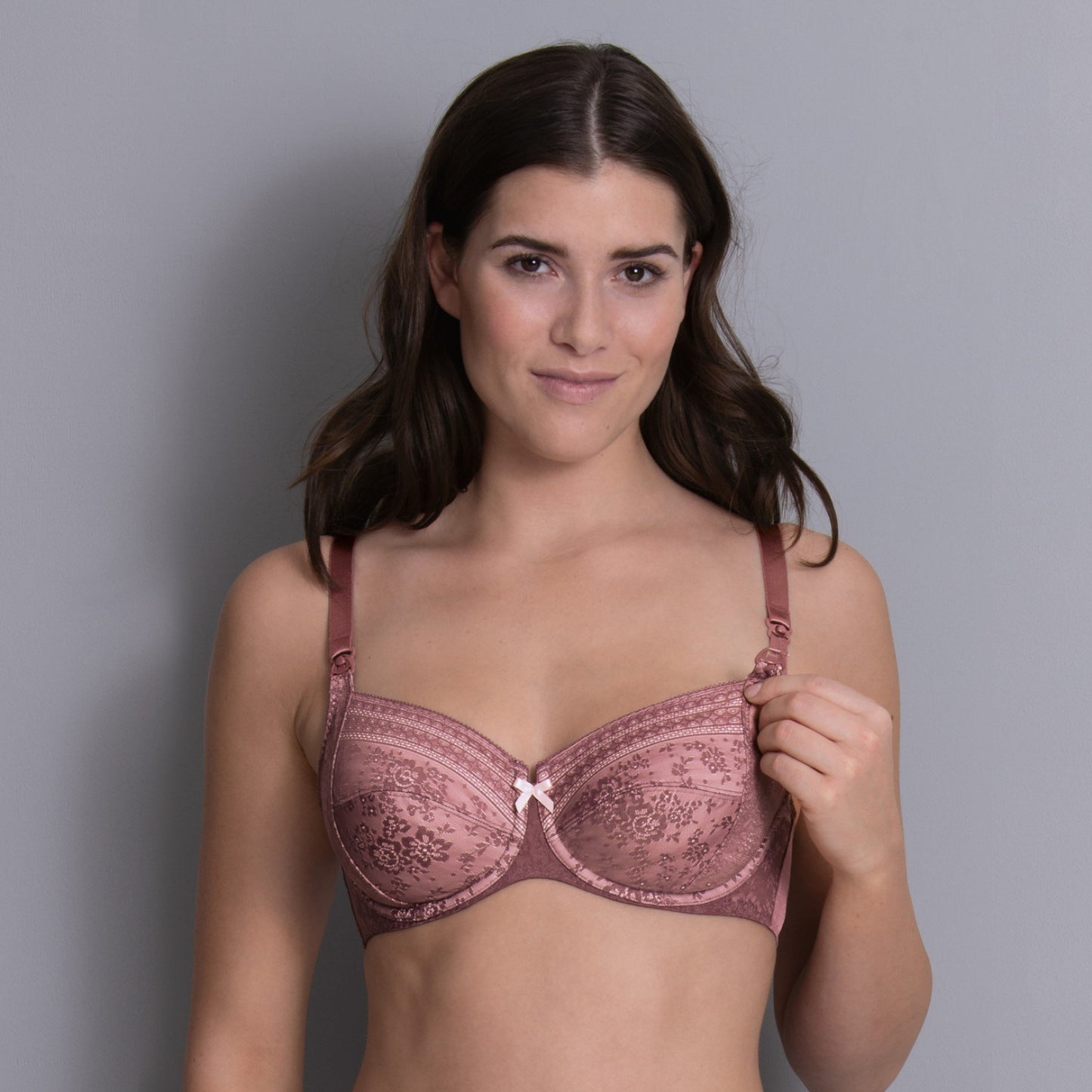 Woman wearing a pink bra against a gray background