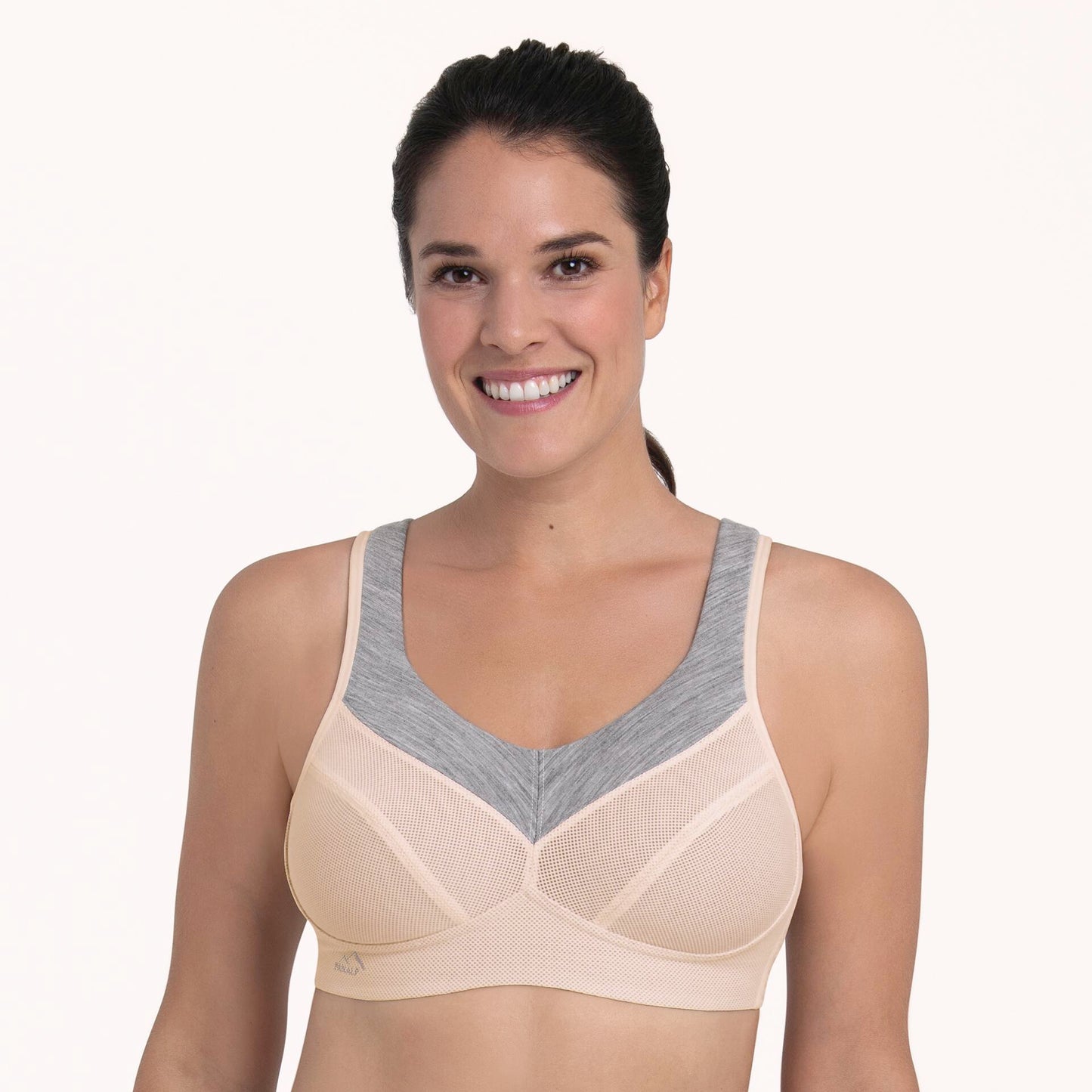 Woman wearing a beige and gray sports bra on a white background