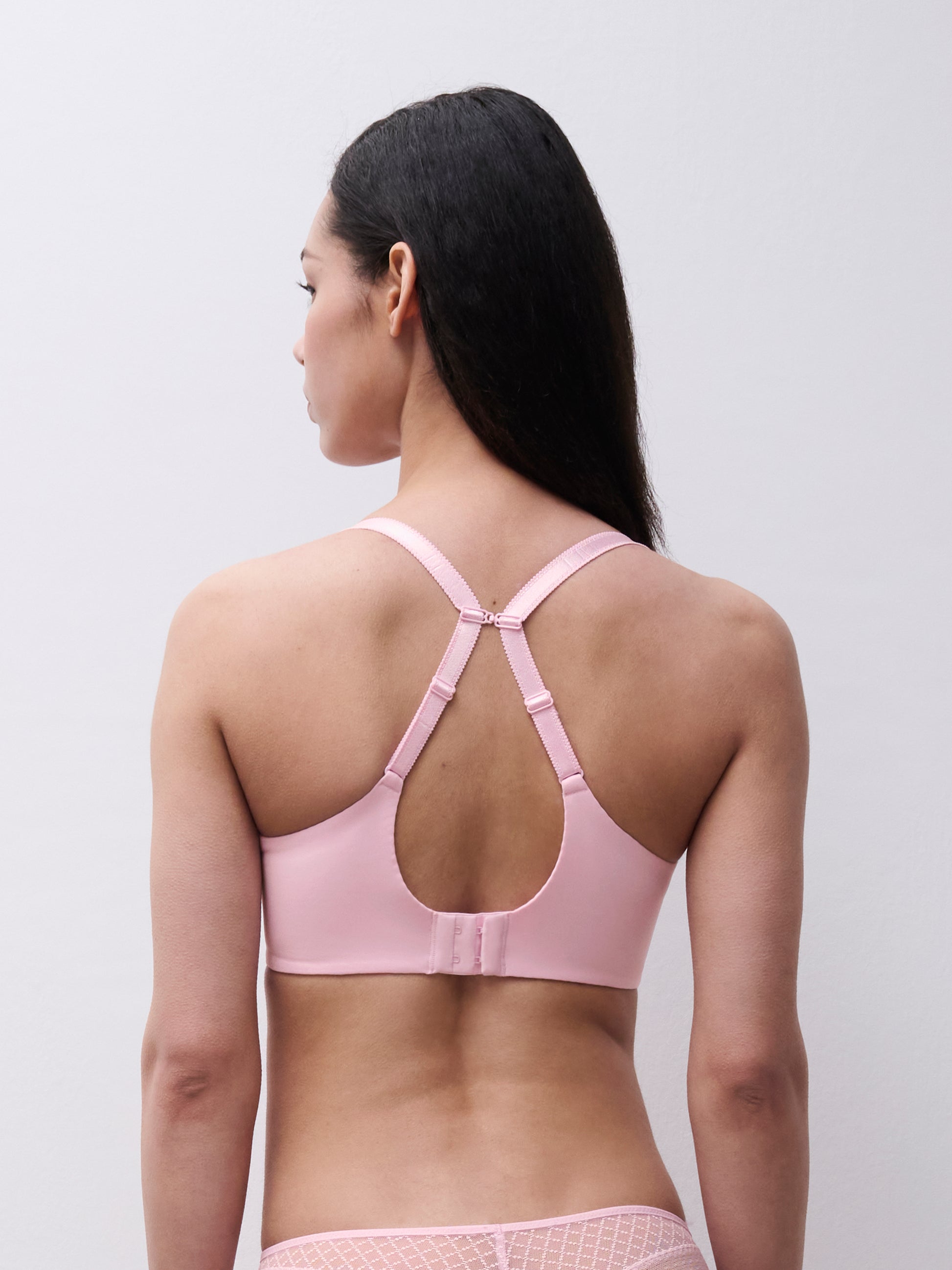 Woman wearing a pink bralette against a plain background
