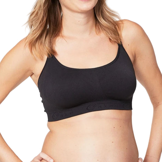 Pregnant woman wearing a black maternity bra and beige underwear on a plain background