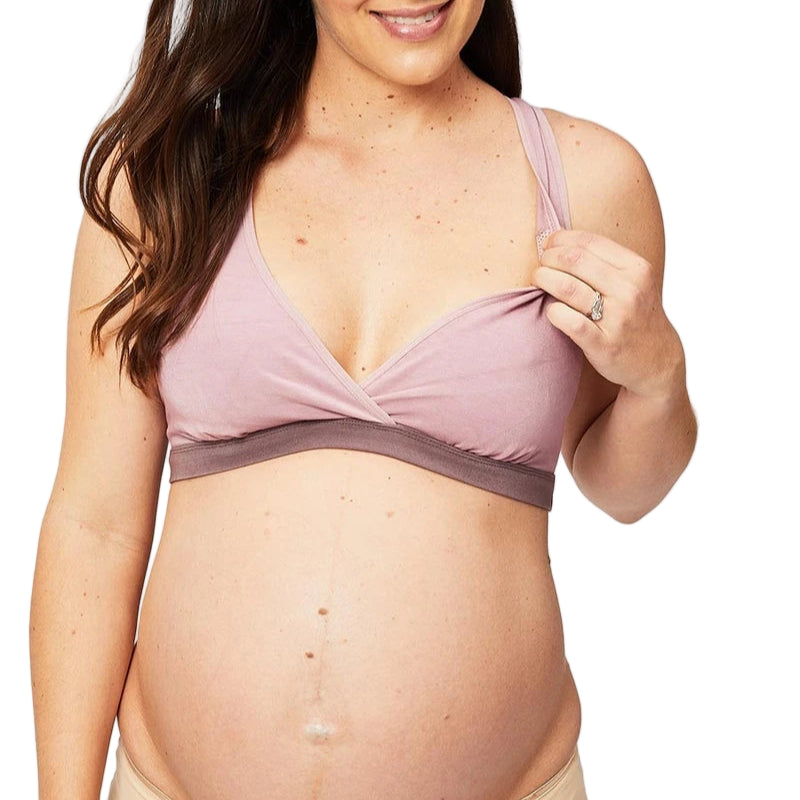 Pregnant woman wearing a pink maternity bra and beige underwear on a white background