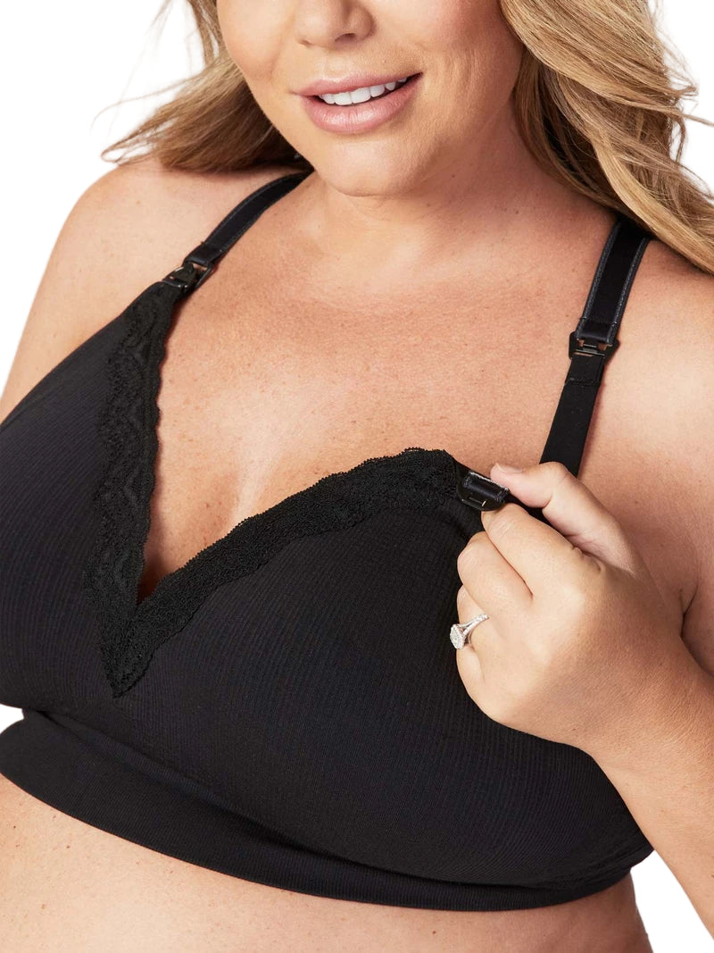 Woman wearing a black bralette with lace trim on a plain background