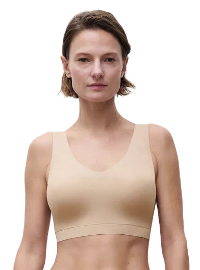 Woman wearing a beige tank top against a plain background