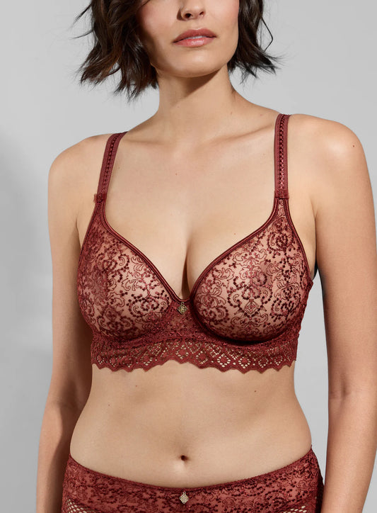 Woman wearing a lace bralette against a plain background