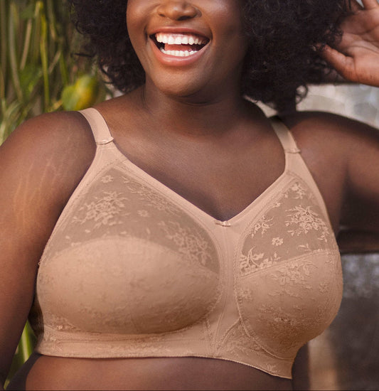 Woman wearing a beige bralette with floral lace details, standing outdoors.