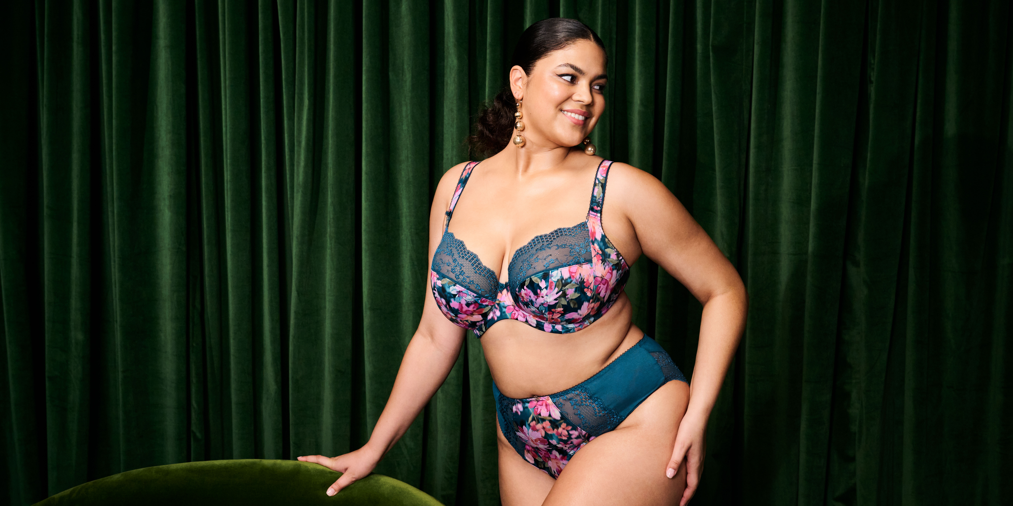 Woman wearing a floral lingerie set against a green curtain background