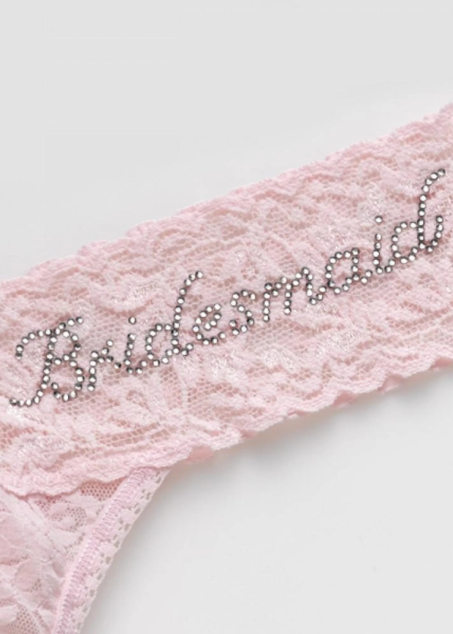 Pink lace sash with 'Bridesmaid' embellishments on a white background