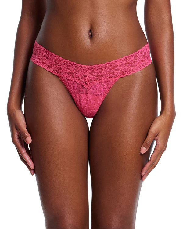 Pink lace thong worn by a model on a white background
