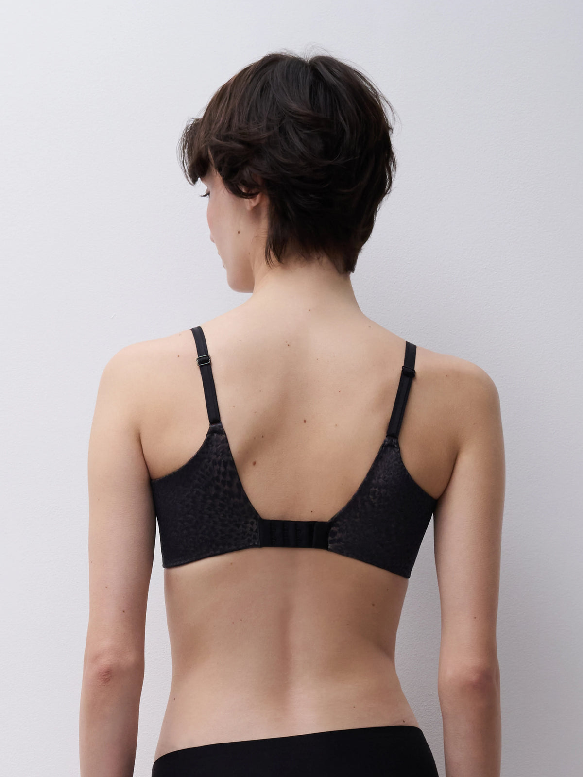 Person wearing a black bra against a plain background
