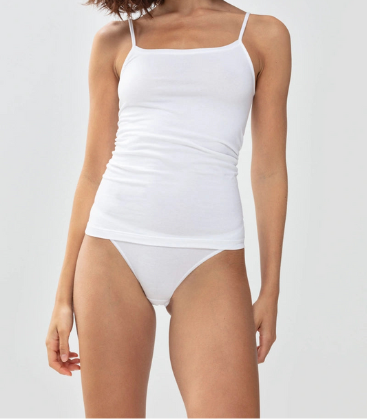 Woman wearing a white tank top and high-waisted bikini bottom on a light gray background