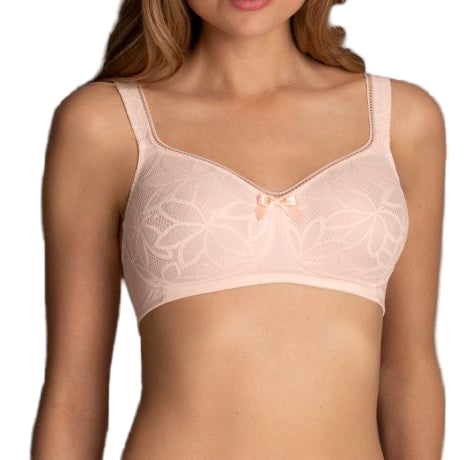 Woman wearing a light pink bra against a gray background