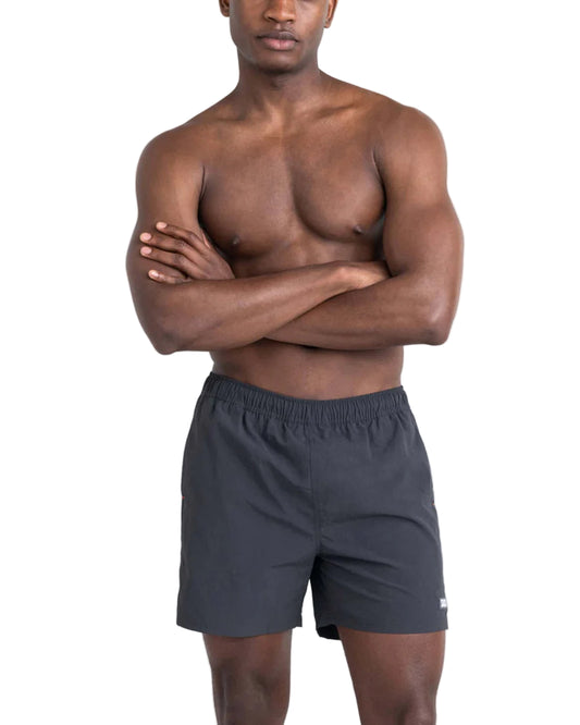Man wearing dark gray swim shorts on a light gray background