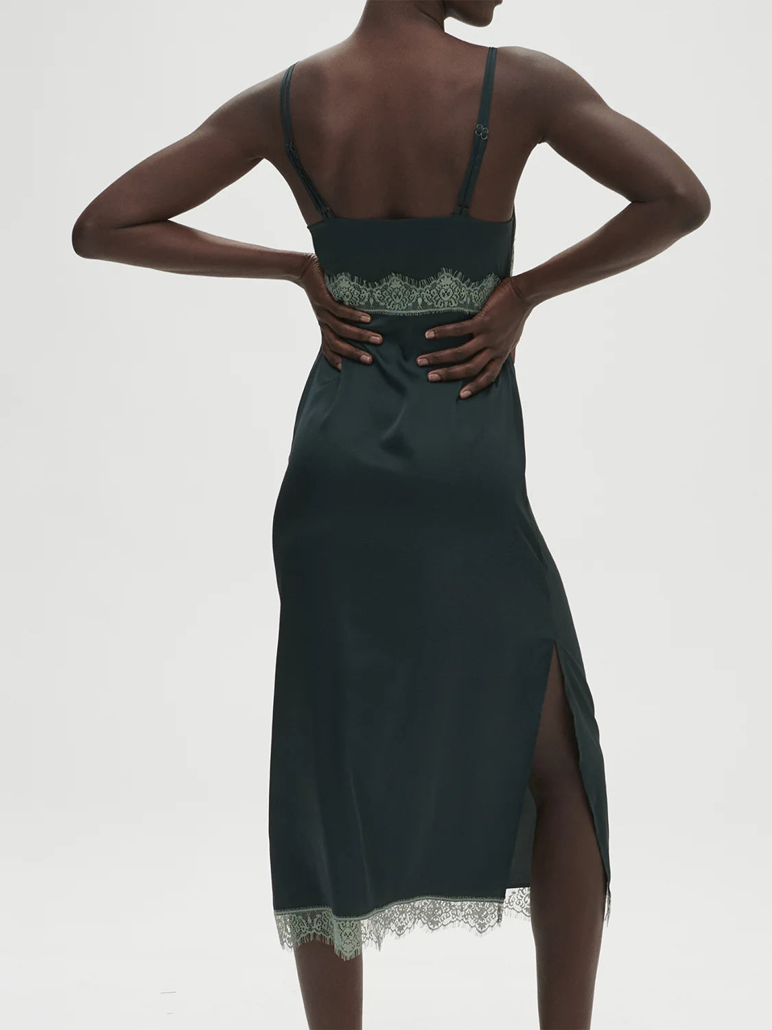 Dark green dress with lace details on a white background