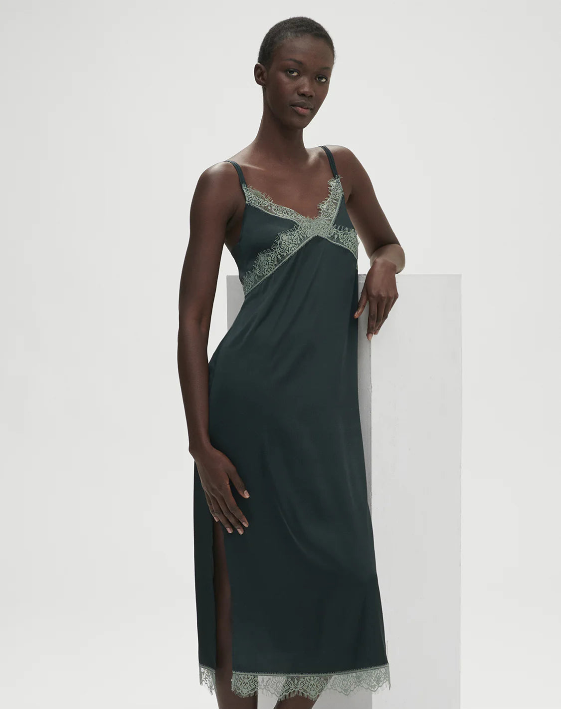 Woman wearing a dark green dress with lace details on a white background