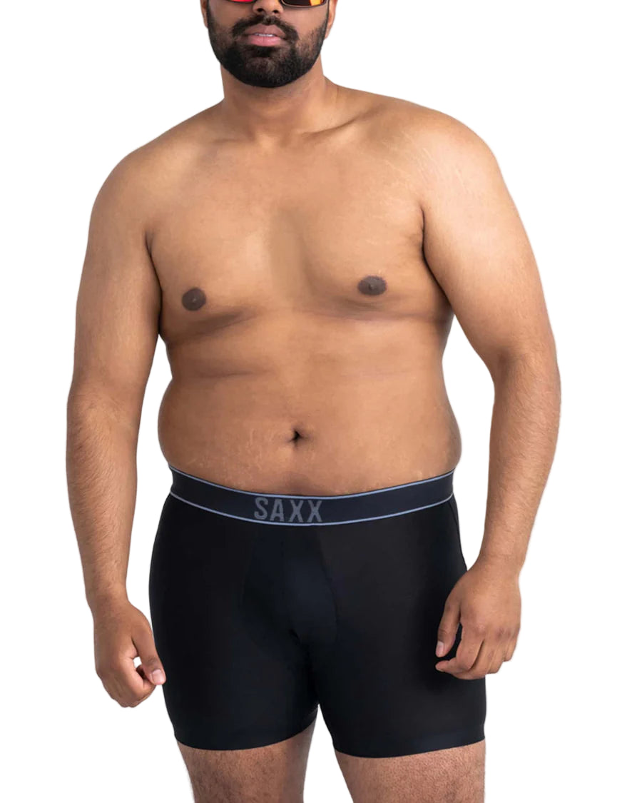 Man wearing black SAXX swimwear on a white background
